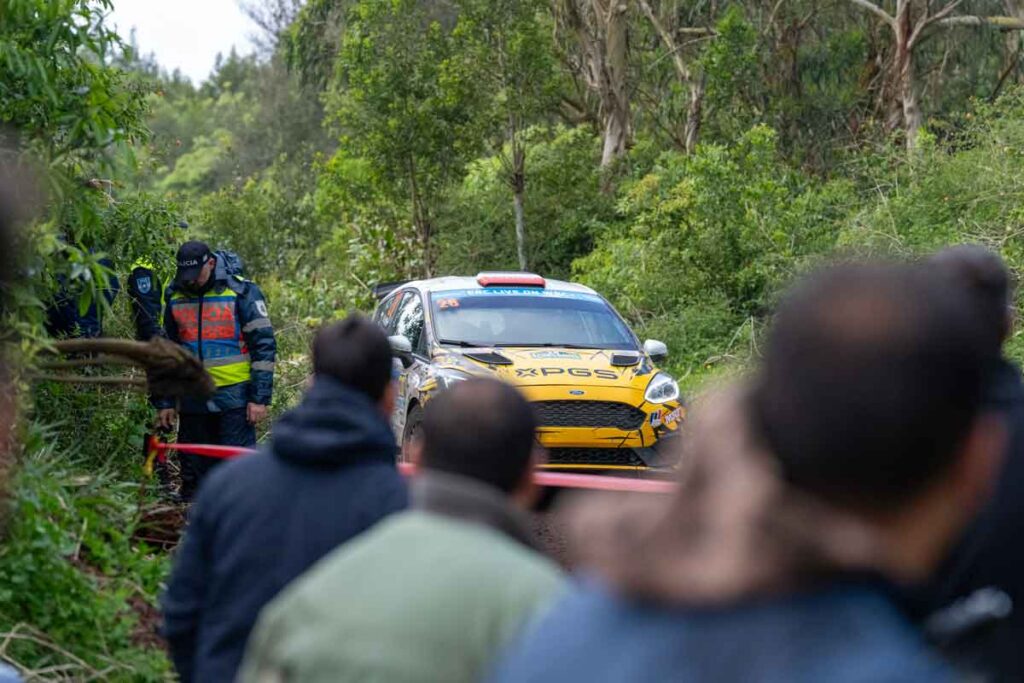 Agente de seguridad controlando al público mientras un coche de rally se aproxima por el tramo