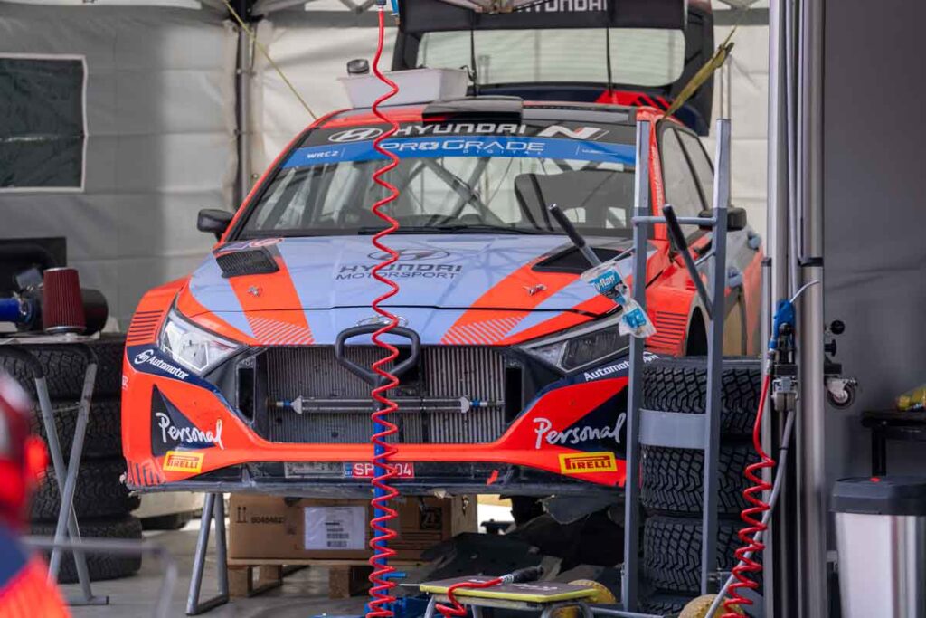 Equipo trabajando en un coche de rally durante la asistencia en el parque de trabajo